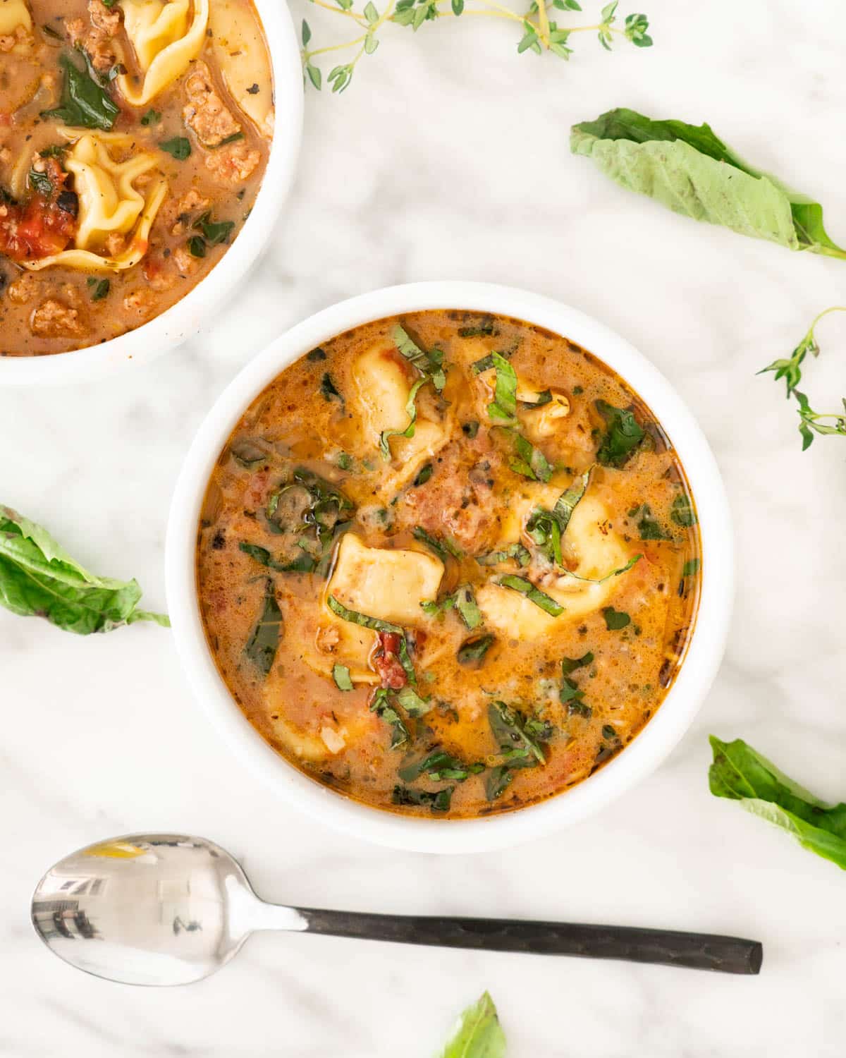 overhead of a bowl of tortellini soup with a spoon